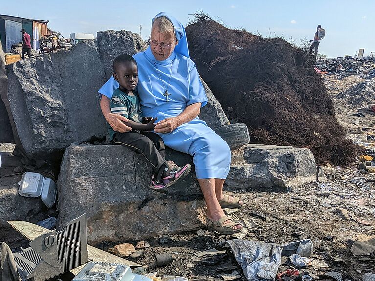 missio-Projektpartnerin Sr. Angelina auf einer Elektroschrotthalde in Ghana neben einem Jungen.