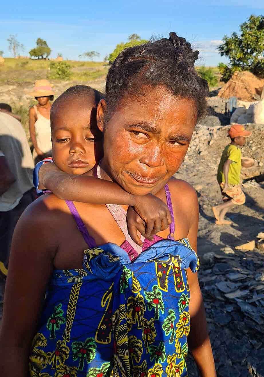 Eine Frau, in auf Madagaskar in den Minen Mica abbaut, trägt ihr kleines Kind auf dem Rücken.