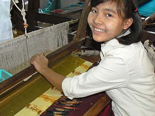 Eine junge Frau in Myanmar arbeitet am Webstuhl