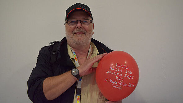 Ein Katholikentagsbesucher hat seinen Luftballon der Aktion #dafürhalteichmeinenkopfhin mit „Integration” beschriftet.