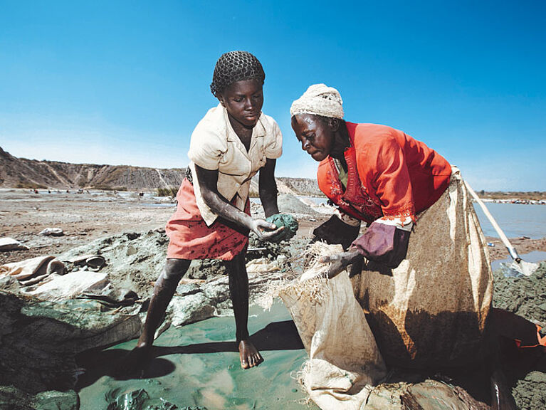 Zwei Frauen im Kongo bauen mithilfe von Schaufeln Rohstoffe ab.