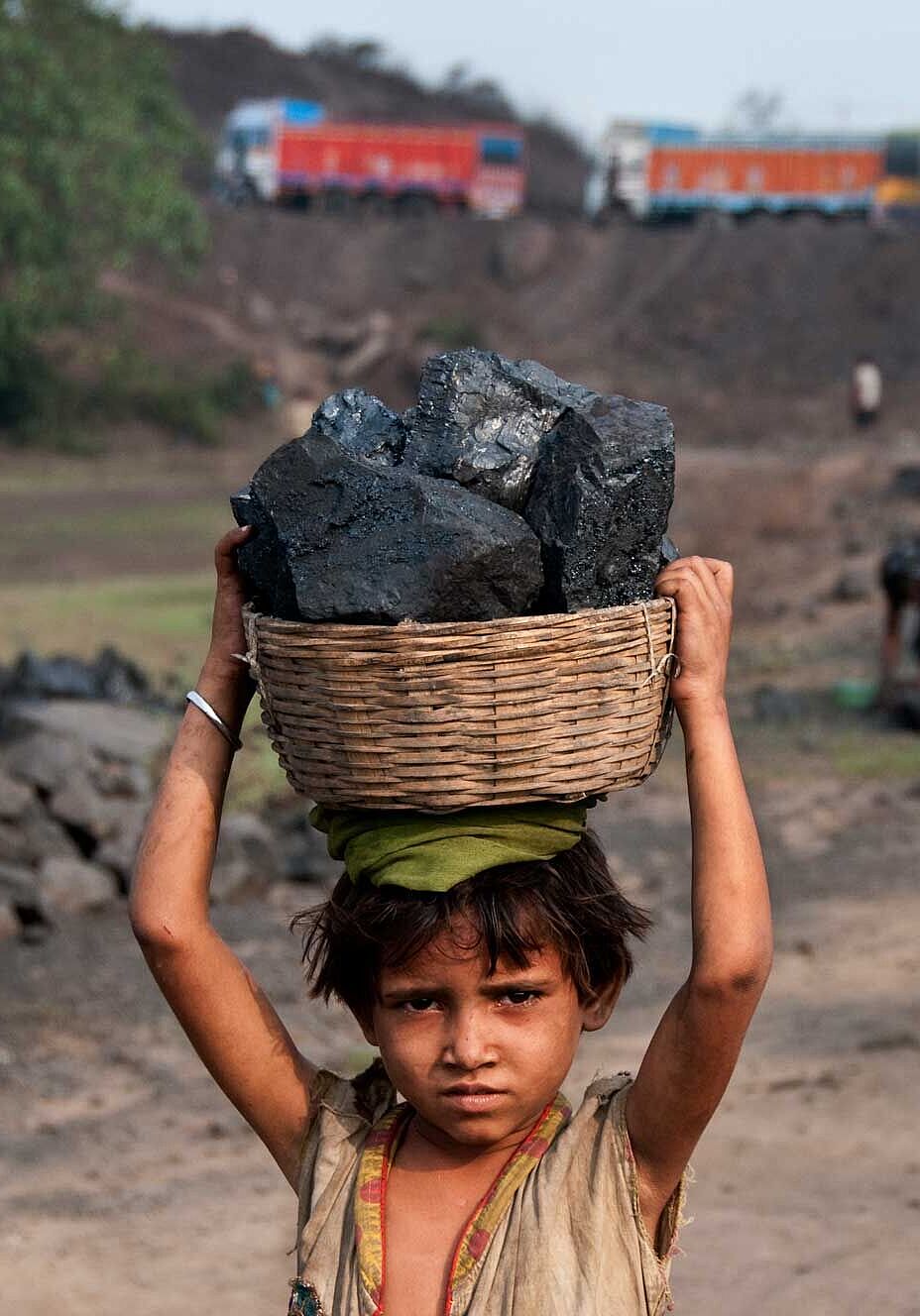 Ein kleines Mädchen trägt auf einer Kohlehalde in Jharia Kohlestücke auf seinem Kopf weg.