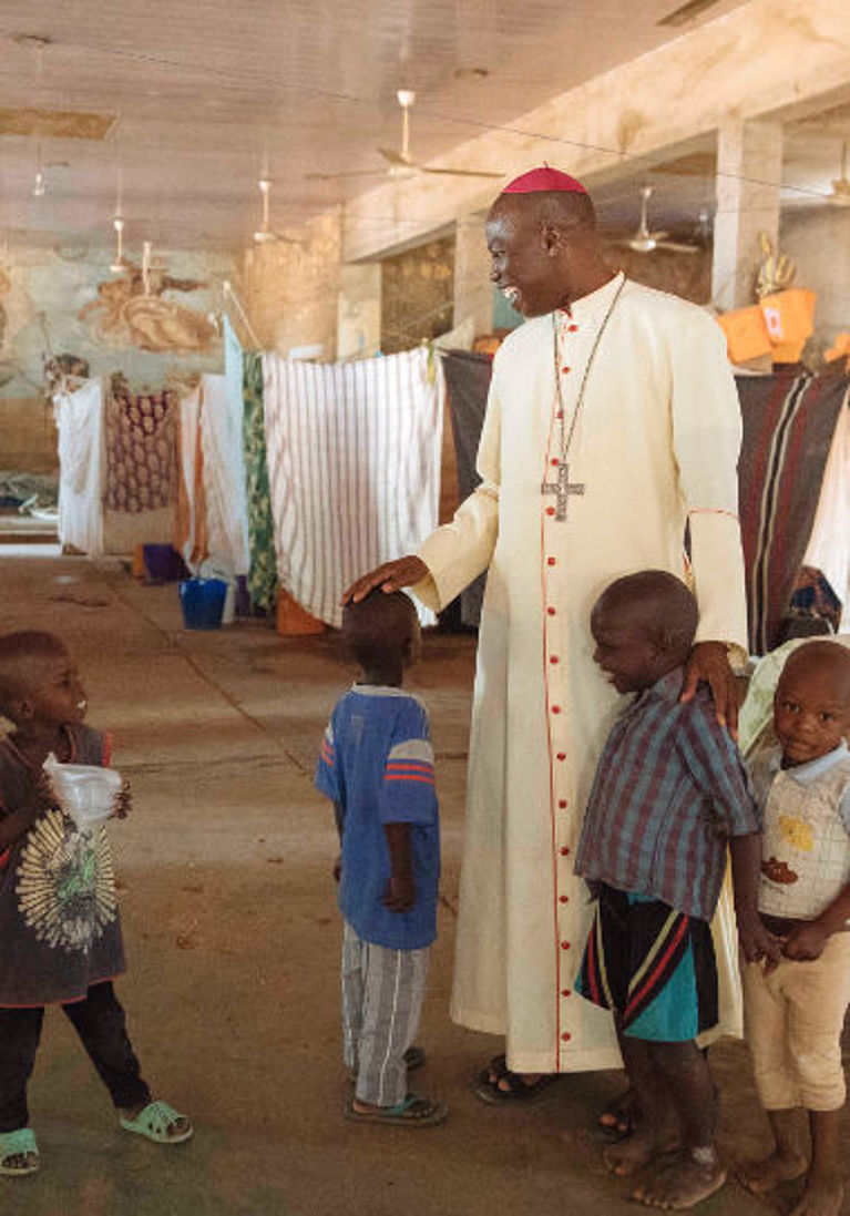 Bischof Stephen Mamza spricht mit Kindern, die mit ihren Familien vor Boko Haram geflohen sind.