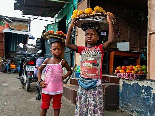 Zwei Mädchen verkaufen auf dem Markt von Cotonou, Benin, Früchte.