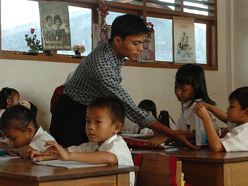 In einem Klassenraum werden Schüler von einem jungen Mann unterrichtet.