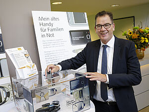 Bundesminister Gerd Müller wirft ein altes Handy in die Sammelbox. 