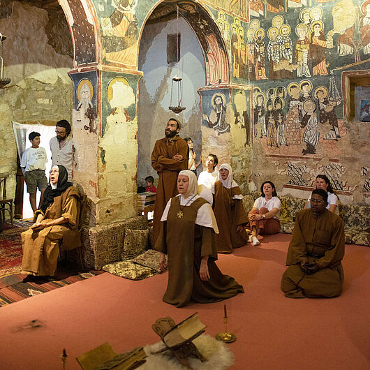 Besucher im orientalischen Kloster Deir Mar Musa in der syrischen Wüste beten zusammen.