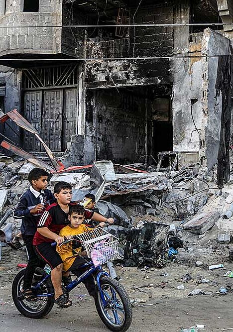 Kinder spielen im Gazastreifen vor ein bombardierten Häusern.