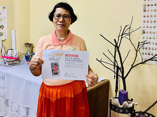 Rhoy Dizon, Vizedirektorin von Action for Nurturing Children and Environment (ANCE), hält die unterzeichnete Petition in den Händen..