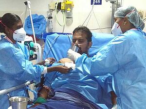 Krankenschwestern versorgen in einem indischen Krankenhaus einen Patienten, der an Covid 19 erkrankt ist.