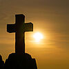 Ein Kreuz vor einem Sonnenuntergang