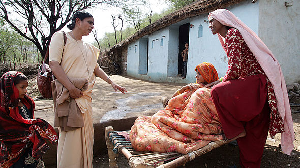 Drei Frauen und ein junges Mädchen unterhalten sich in einem Dorf in Indien.