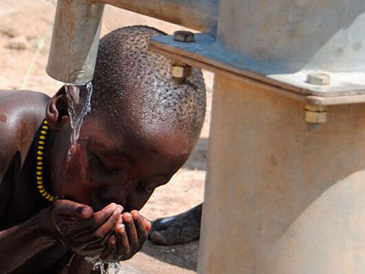 Ein Kind des äthiopischen Nomadenstammes Nyangatom trinkt an einem Brunnen.