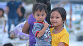 Ein philippinisches Mädchen trägt den kleineren Bruder.