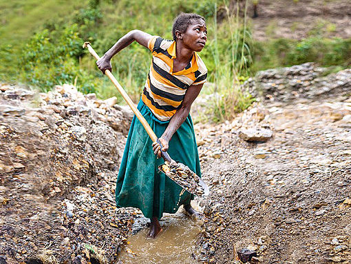 Eine Frau im Kongo baut mithilfe einer Schaufel Rohstoffe ab.