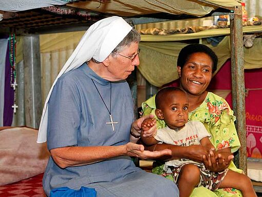 Schwester Lorena und eine Frau mit ihrem Kind auf dem Schoß.