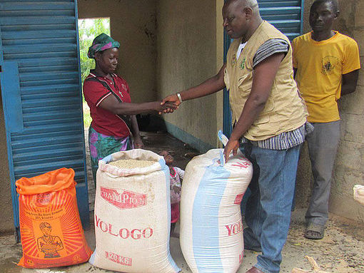 Ein Mitarbeiter von OCADES Burkina Faso verteilt Lebensmittel an eine vertriebene Frau.