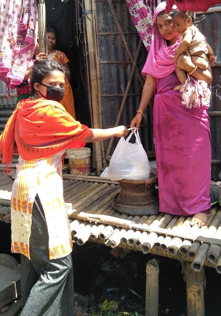 Eine kirchliche Mitarbeiterin verteilt in einem indischen Dorf Lebensmittel.