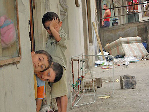 Drei Jungen blicken aus einem Haus in der schwer beschädigten syrischen Stadt Homs.
