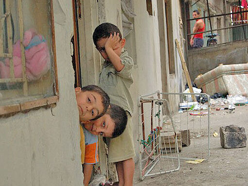 Drei Jungen blicken aus einem Haus in der schwer beschädigten syrischen Stadt Homs.