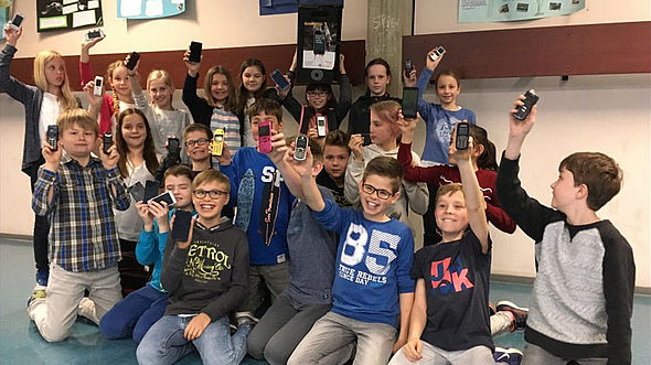 Foto von Schülerinnen und Schüler des Gymnasiums Thomaeum in Kempen, die Handys hochalten, die sie für die Handysammelaktion zugunsten von missio gesammelt haben.