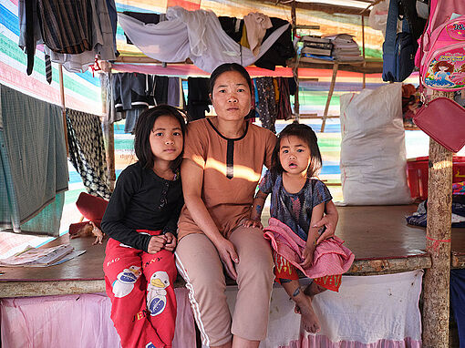 Eine Mutter sitzt mit ihren beiden Töchtern im Flcühtlingslager Zokhawthar, Nordostindien.