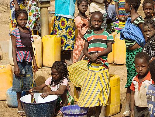 Kinder holen Wasser an einem Brunnen in Burkina Faso.