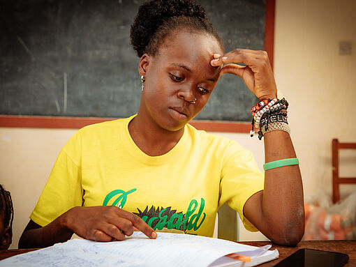 Das Foto zeigt die Leiterin einer Mikrofinanzgruppe mit ihren Haushaltsbüchern in Nairobi. 