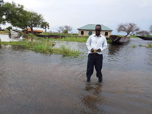 Pfarrer Marko Tongo watet nach Überschwemmungen durch das Wasser in der Gemeinde Mingkaman, Südsudan.