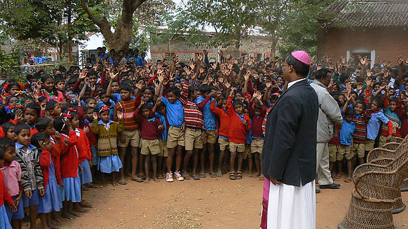 Ein Priester steht vor vielen indischen Schülerinnen und Schülern.