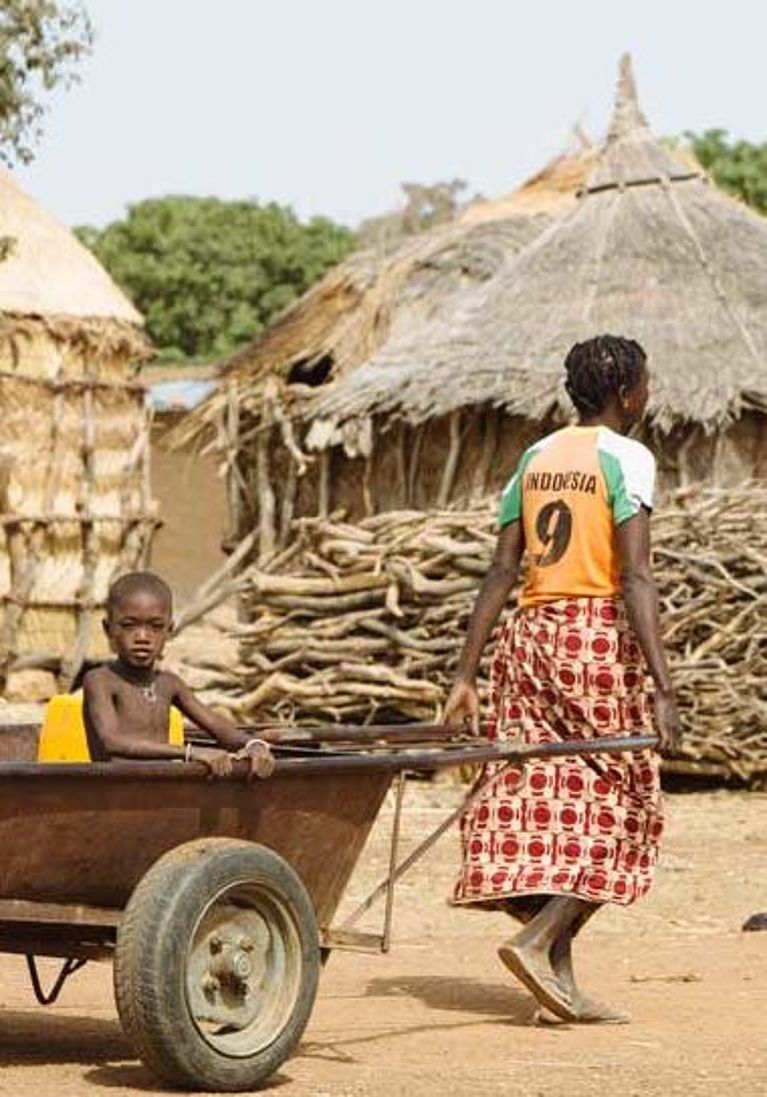 Eine Mutter zieht ihr Kind auf einem Karren, Burkina Faso.