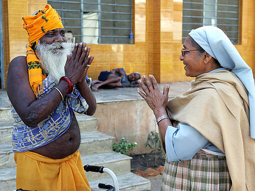 Schwester Damien und ein indischer Mann stehen sich im Zentrum Asha Dham Ashram mit gefalteten Händen gegenüber.