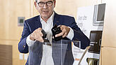 Bundesminister a.D. Gerd Müller wirft Handys in eine Spendenbox. 