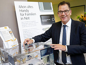 Bundesminister Gerd Müller wirft ein Handy in die Annahmestelle des BMZ.