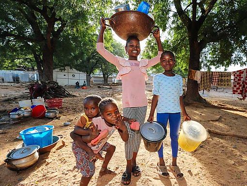 Vier Flüchtlingskinder in Yola, Nigeria, tragen Eimer und Schüsseln.