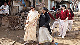 Frauen und Mädchen gehen durch ein Dorf in Indien.