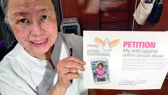 Die filipinische Schwester Mary John Mananzan hält die unterzeichnete Petition hoch. 