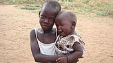 Ein Kind hält ein weinendes Baby auf dem Arm.