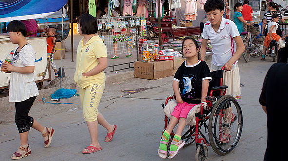 Ein Mädchen sitzt im Rollstuhl und kommt nur aus ihrer Einrichtung, wenn sie jemand mitnimmt. 