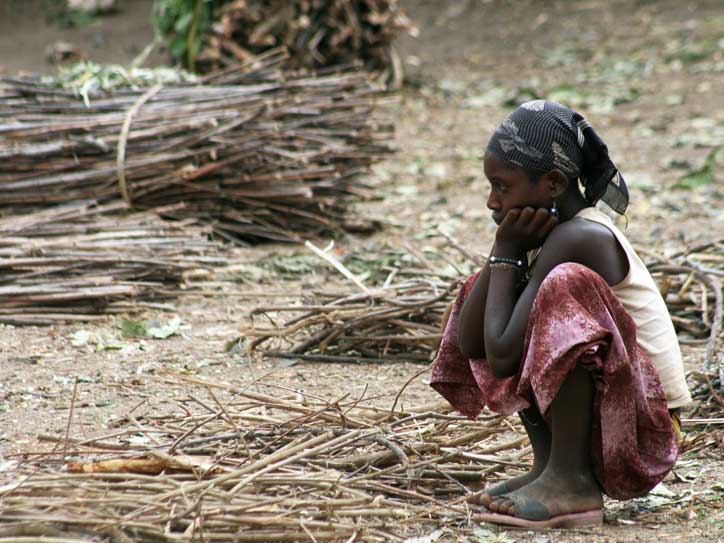 Ein Mädchen der Volksgruppe Tigray hockt am Boden.