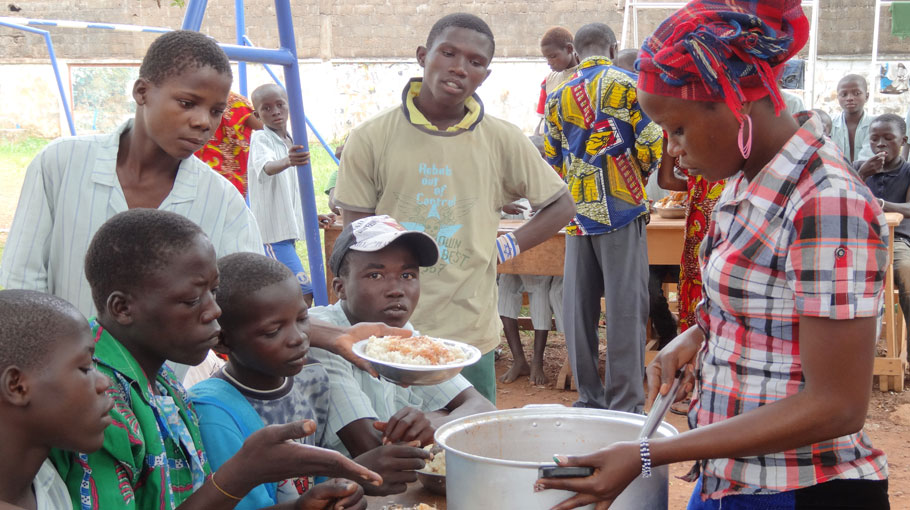 Eine Junge Frau im Flüchtlingscamp verteilt Essen an Jugendliche.
