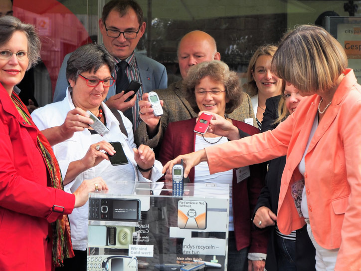 Eine Gruppe in Bonn steckt Handys in eine Sammelbox. 